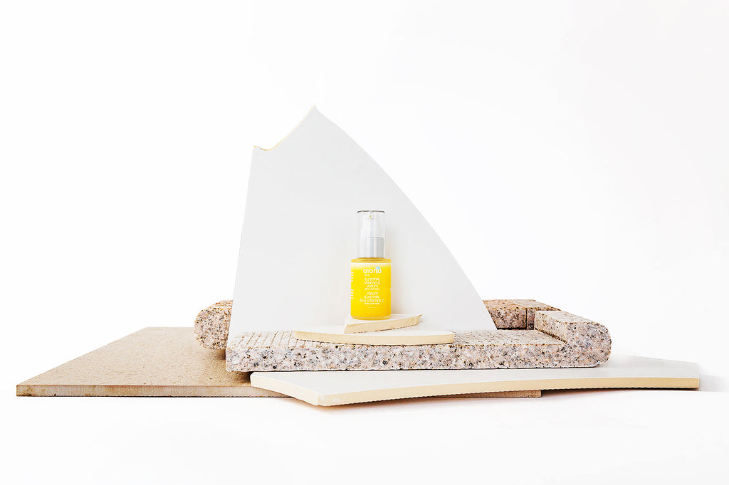 yellow serum bottle against beige stone background