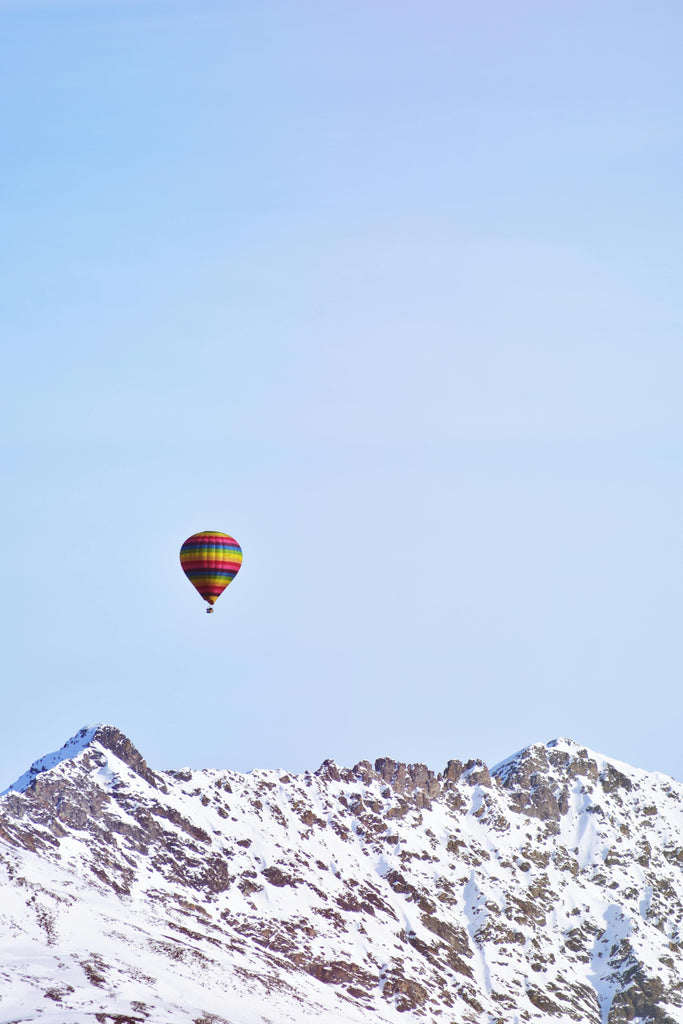Hot air balloon flying over snowy mountains 