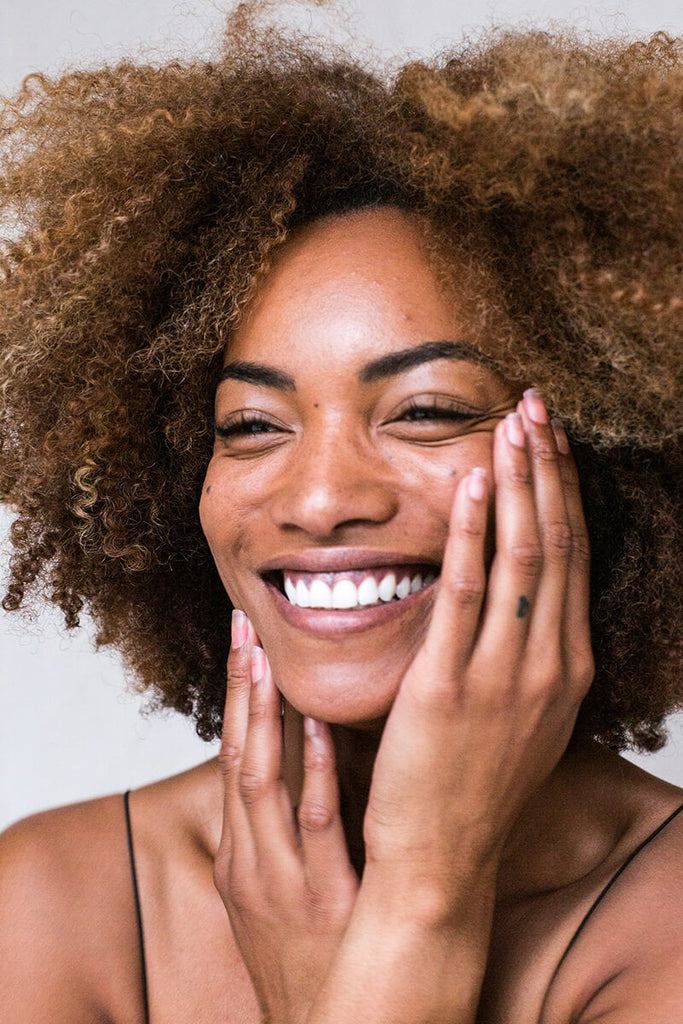 woman smiling and touching her face