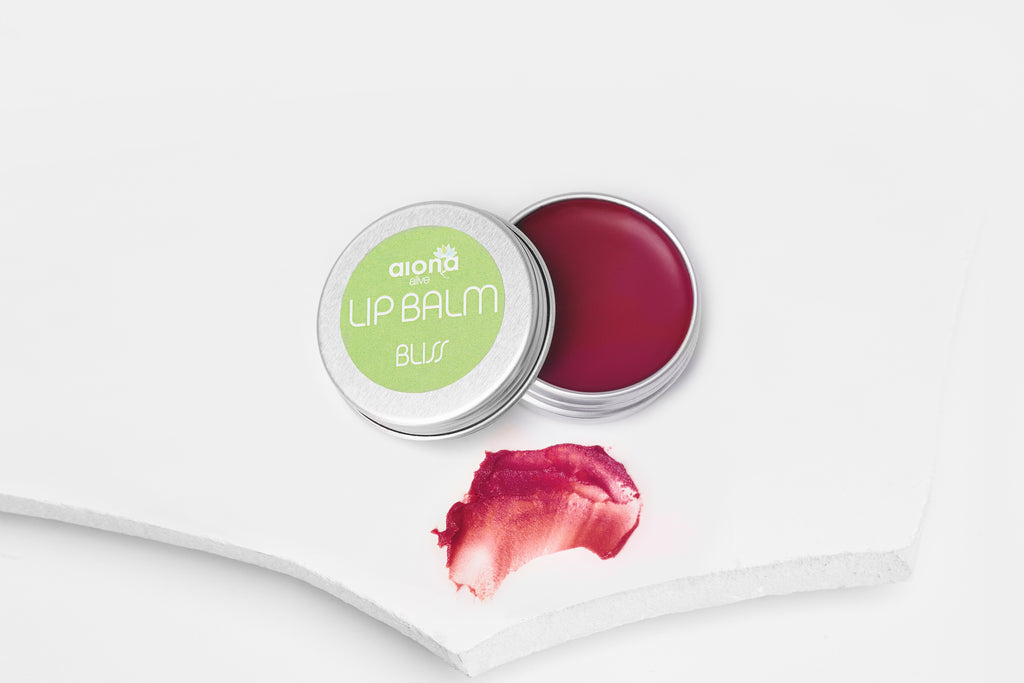 Lip balm container with a swatch of raspberry pink lip balm on a white background