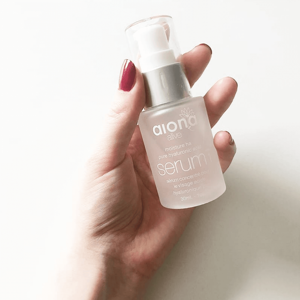 hand holding serum bottle with red nails